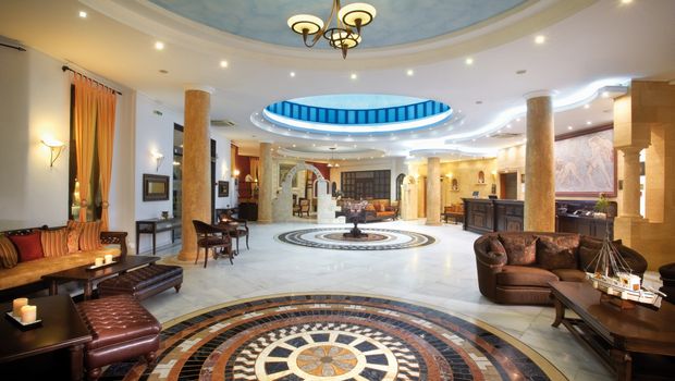 Prächtige Hotellobby mit kunstvoll gemustertem Marmorboden, eleganten Säulen und stilvollen Sitzbereichen – die einladende Atmosphäre wird durch eine imposante Kuppel mit Oberlicht und luxuriöse Details unterstrichen.