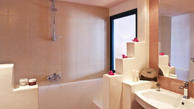 Helles Badezimmer mit Badewanne, großem Spiegel und liebevollen Details wie Dekoblumen – für entspannte Wohlfühlmomente.