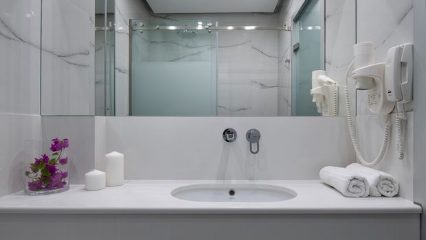 Modernes Badezimmer in elegantem Marmor-Design mit großer Dusche, breitem Spiegel und stilvollen Details – ideal für entspannte Wohlfühlmomente während des Urlaubs.