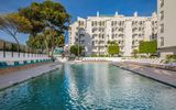 Außenansicht des Occidental Puerto Banús Hotels mit großem Swimmingpool, Sonnenliegen und mediterraner Gartenanlage – ideal für entspannte Urlaubstage in der Sonne.