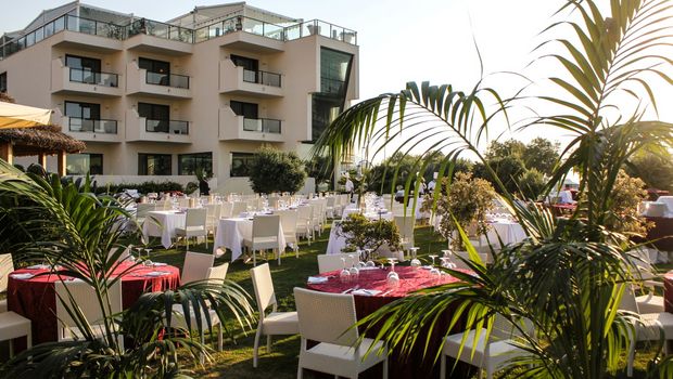 Stilvoll gedeckte Tische auf einer gepflegten Gartenanlage vor einem modernen Hotelgebäude – die perfekte Kulisse für ein romantisches Dinner unter freiem Himmel.