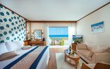 Modern eingerichtetes Zimmer mit gemütlicher Sitzecke und herrlichem Ausblick auf das türkisblaue Meer.