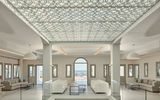 Elegante Hotel-Lobby mit kunstvoller Decke, modernen Sitzgruppen und direktem Blick auf das funkelnde Meer – stilvoller Empfang in traumhafter Umgebung.