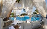 Romantische Daybed-Liege mit weißen Vorhängen direkt am Pool – perfekter Ort zum Entspannen und Träumen unter der mediterranen Sonne mit Blick auf das erfrischende Wasser.