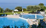 Zwei miteinander verbundene Außenpools mit Panorama-Meerblick, umgeben von Sonnenliegen, Olivenbäumen und mediterranem Garten – ein Ort zum Entspannen und Genießen.