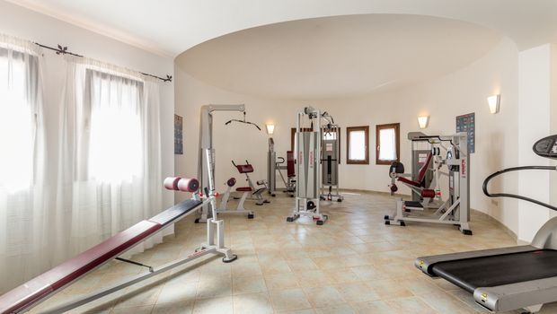 Heller Fitnessraum mit mehreren modernen Kraftgeräten, Hantelbank und Laufband – ideal für ein ausgiebiges Workout im Urlaub.