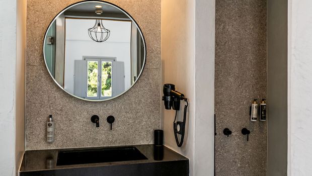 Modernes Bad mit stilvollem Waschbereich, schwarzem Waschbecken, großzügigem Spiegel und begehbarer Dusche mit Regenduschkopf – alles in harmonischen Naturtönen gehalten.