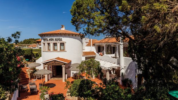 Charmantes Hotel im mediterranen Stil mit weißer Fassade, Terrakottadach und idyllischer Außenterrasse – umgeben von grüner Natur.